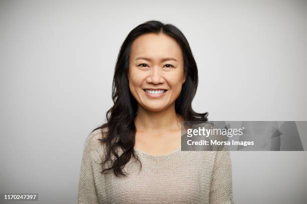 smiling young woman against white background - asia stock-fotos und bilder