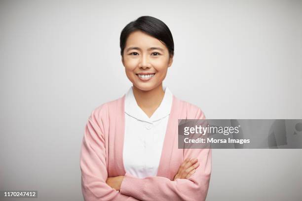 happy female nurse in uniform with arms crossed - east asian ethnicity stock pictures, royalty-free photos & images