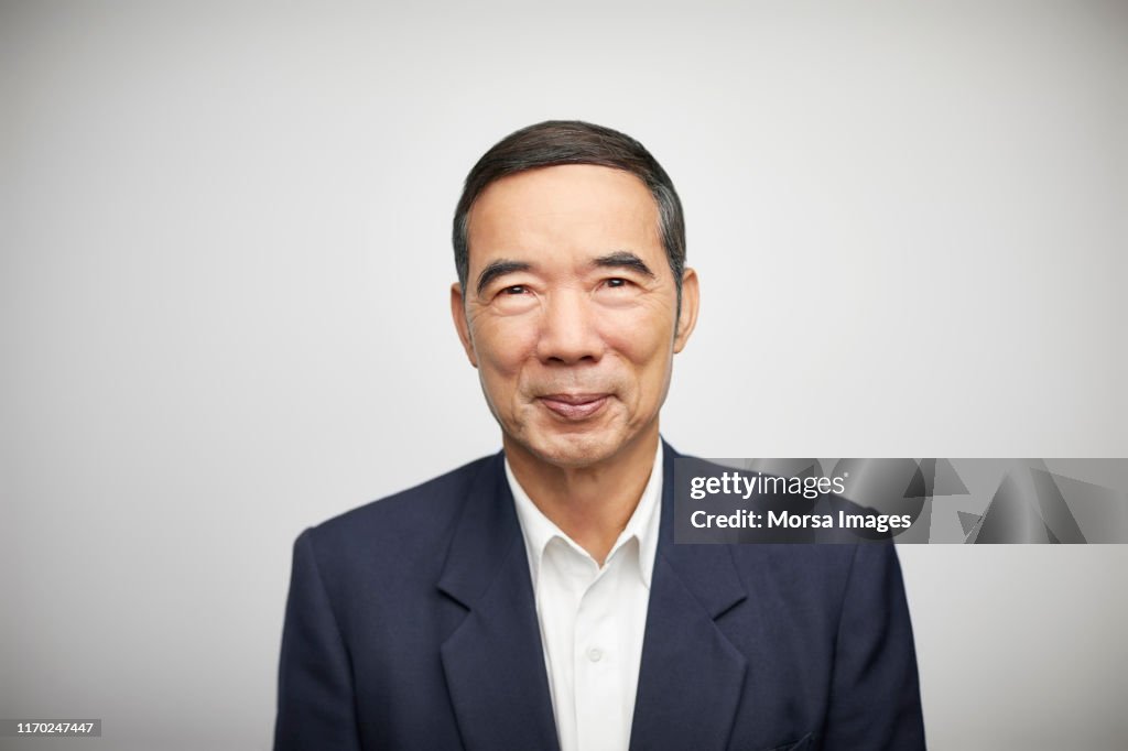 Smiling senior businessman against white background