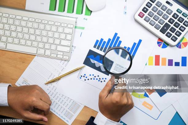 holding magnifying glass  for looking and analysis financial data, business finances and saving concept. - audit stockfoto's en -beelden