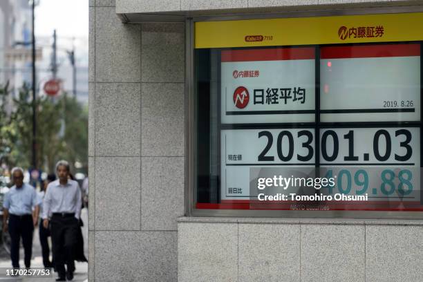 Pedestrians walk near an electronic stock board displaying the Nikkei 225 Stock Average figure on August 26, 2019 in Tokyo, Japan. Japanese stocks...