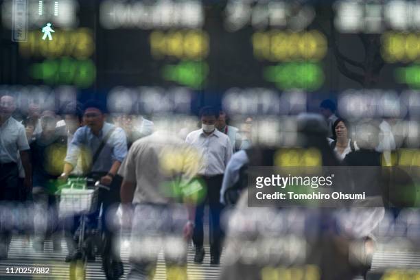 Pedestrians are reflected in an electronic stock board outside a security firm on August 26, 2019 in Tokyo, Japan. Japanese stocks dropped and the...