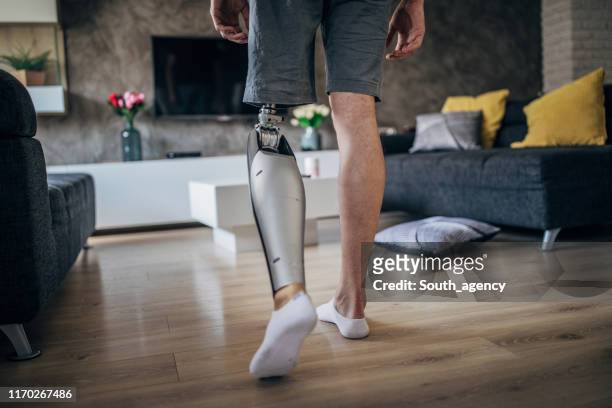 guy with one prosthetic leg in living room - legs walking stock pictures, royalty-free photos & images