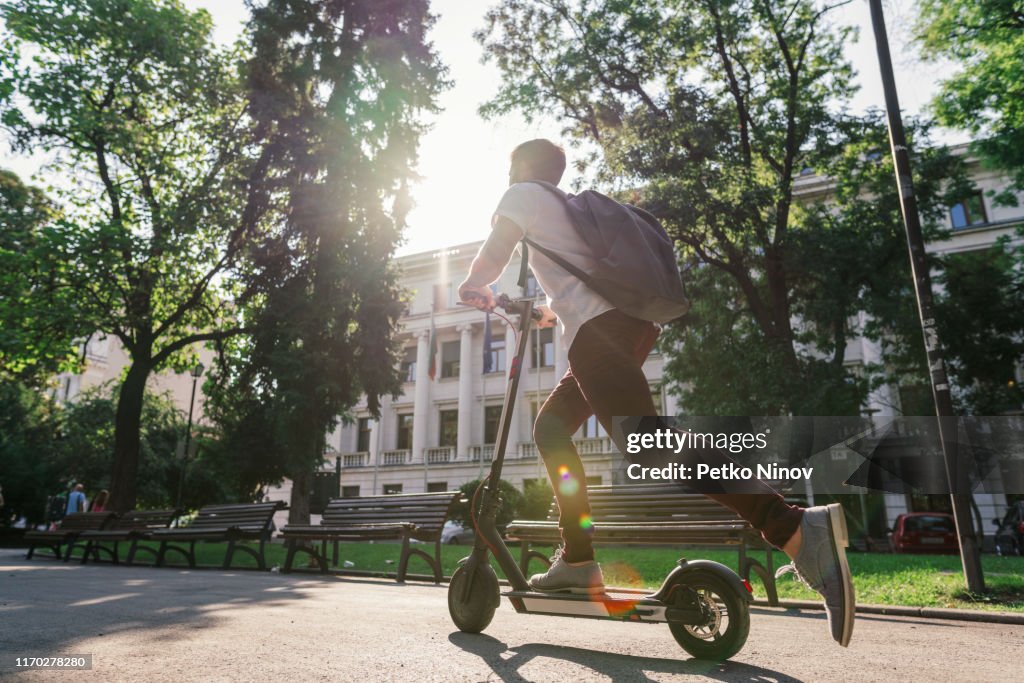 Man riding e-scooter through the city park
