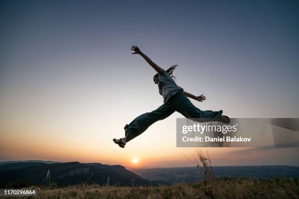 jump high and express yourself. over the sun. - leap forward stock pictures, royalty-free photos & images