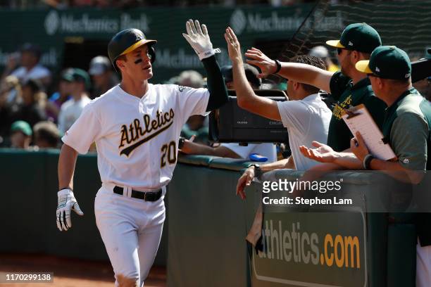 Mark Canha of the Oakland Athletics is being congratulated by teammates after being driven in by Jurickson Profar during the fourth inning against...