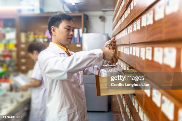 a chinese male doctor weighs traditional chinese medicine - chinese herbal medicine stock pictures, royalty-free photos & images