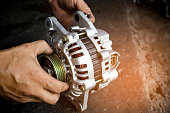 Change new car alternator with hand in the garage or auto repair service center, as background automotive concept. Dark tone.