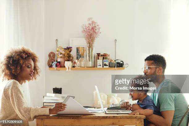 ouders die technologie gebruiken terwijl ze met een zoon zitten - couple at table with ipad stockfoto's en -beelden