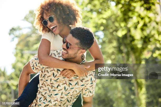 cheerful young couple enjoying piggyback ride - honeymoon stock pictures, royalty-free photos & images