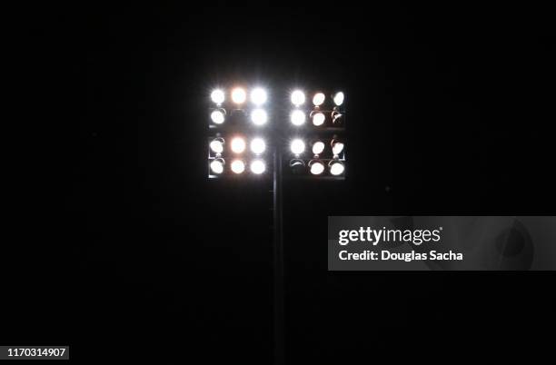 illuminated stadium lights on a dark sky - flutlicht stock-fotos und bilder