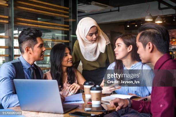 moslim teamleider moedigt haar teamlid aan tijdens een zakelijke bijeenkomst - membership community business stockfoto's en -beelden