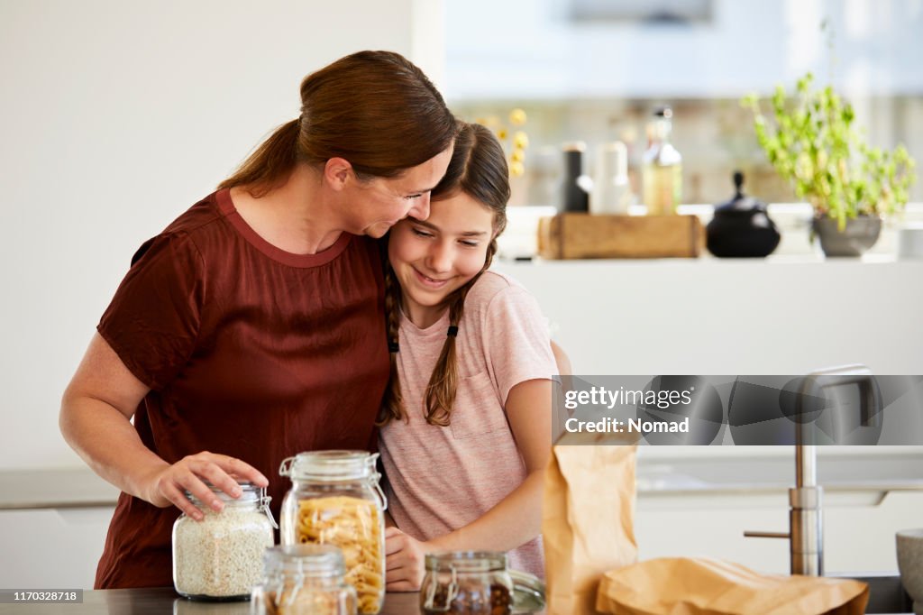 Madre abrazando a la niña después de desempacar comestibles