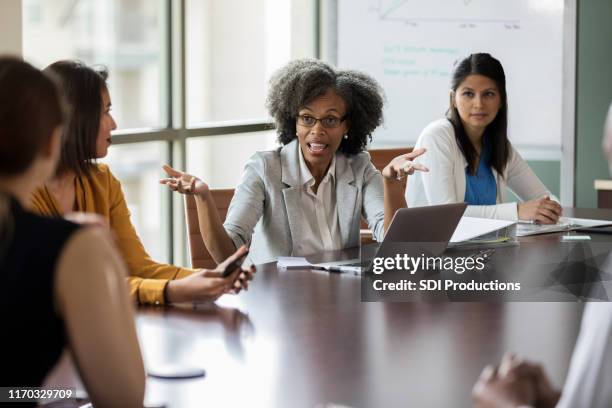 concerned businesswoman talks with colleagues - team conflict stock pictures, royalty-free photos & images