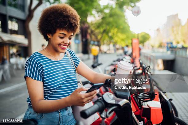 young woman surfing the net on her way to work - coffee bike stock pictures, royalty-free photos & images