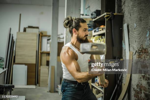 hübscher mann bricht eine wand mit einem hammer - heavy demolition stock-fotos und bilder