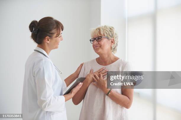 female doctor delivering good news to mature female patient. - happy surprise stock pictures, royalty-free photos & images