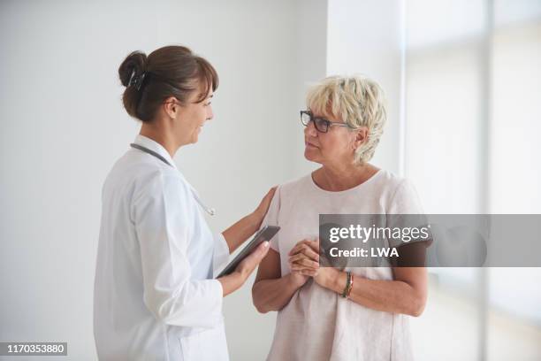 female doctor delivering good news to mature female patient. - heilbehandlung stock-fotos und bilder