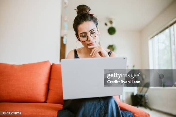 vrouw online werken op laptop thuis - twijfel stockfoto's en -beelden