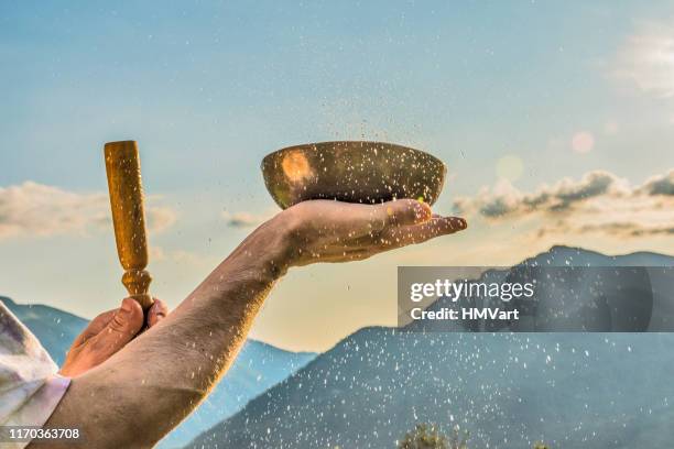 close up man hands playing tibetan handcrafted singing bowls against mountain at the sunset - tibetan culture stock pictures, royalty-free photos & images