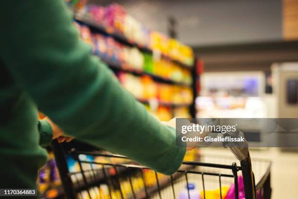 junge frau beim einkaufen in einem supermarkt - frau einkaufswagen ernst stock-fotos und bilder