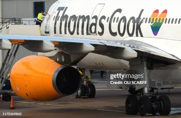 Worker closes the door of a Thomas Cook passenger aircraft after it landed at Manchester Airport in Manchester, northern England on Septmeber 23,...