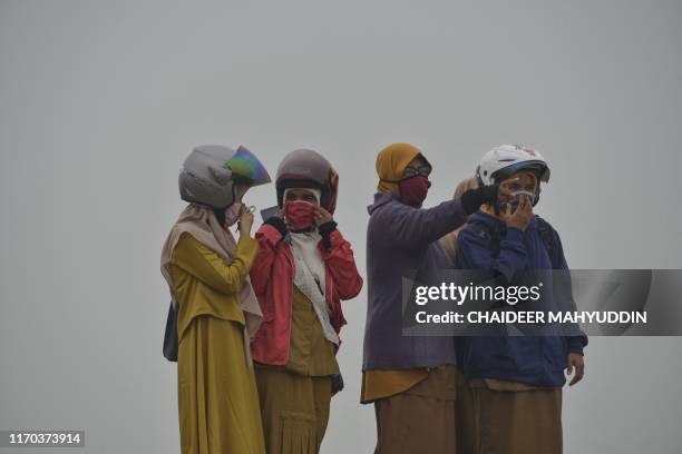 People wear masks due to thick haze, caused by smog-belching forest fires in Indonesia, near the Sultan Iskandar Muda airport in Aceh province on...