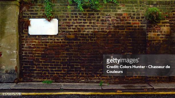 london weathered brick wall with ivy and road - straatnaambord stockfoto's en -beelden
