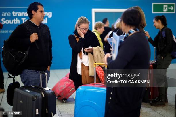 Officials talk with affected passengers arriving at the closed Thomas Cook check-in desk at the South Terminal of London Gatwick Airport in Crawley,...