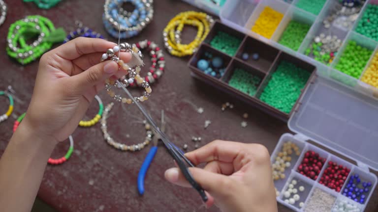 https://media.gettyimages.com/id/1170379567/video/female-hands-making-handmade-jewelry-with-little-balls-and-stones.jpg?b=1&s=640x640&k=20&c=TSu2s4uZPKENSDFAtZxF2Ui2rpr6k23UIsk3SuF7YZk=