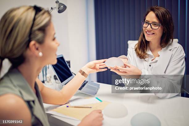 doctor is showing breast implants to young woman in beauty treatment clinic - tratamento a laser imagens e fotografias de stock