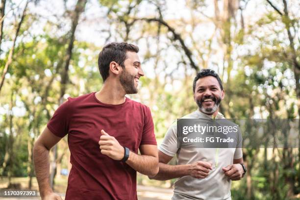 freunde laufen zusammen in einem park - fitness tracker stock-fotos und bilder