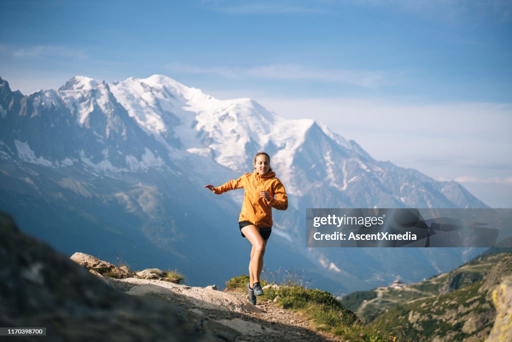 Young woman trail runs in mountains