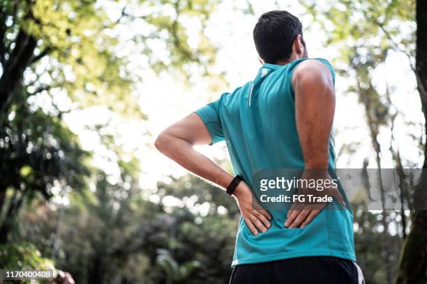 運動員在公園裡感到背痛 - 下背部痛 個照片及圖片檔