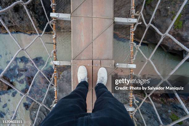 looking down from the carrick-a-rede rope bridge, highlighting the almost 100 feet drop below - northern ireland rope bridge stock-fotos und bilder