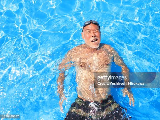 floating senior man on the rooftop pool - rooftop pool stock-fotos und bilder