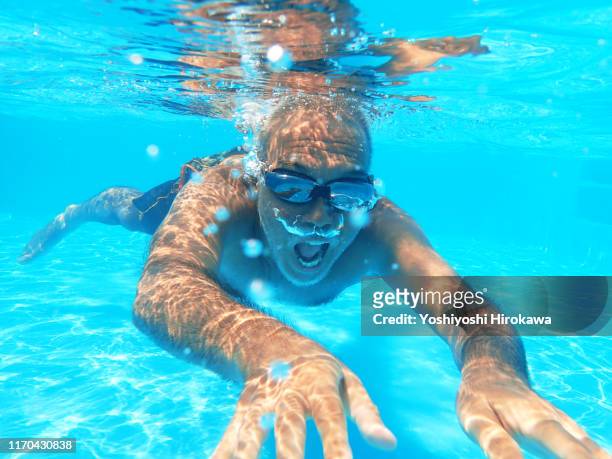 57 year old man swimming underwater in pool - 55 year old male stockfoto's en -beelden