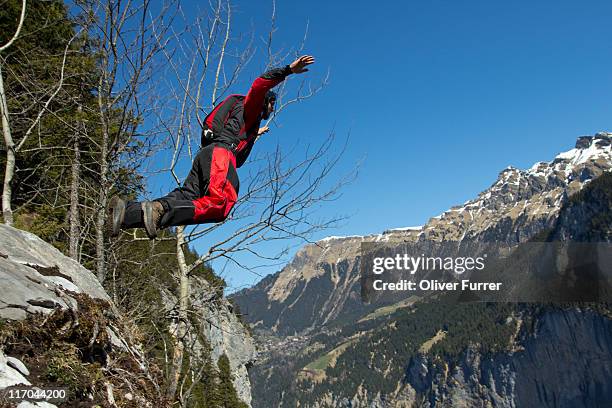 man is jumping of a cliff down the valley. - lauterbrunnen stock pictures, royalty-free photos & images