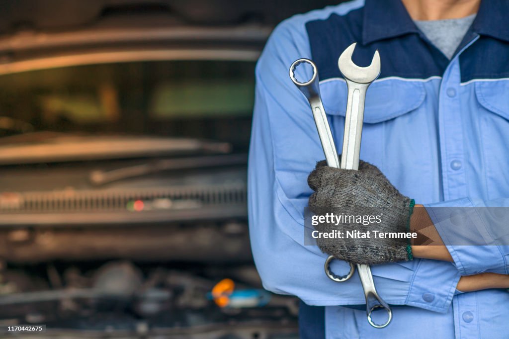 Professional Mechanic in the garage. Auto repair garage. Hands of car mechanic with wrench in garage.