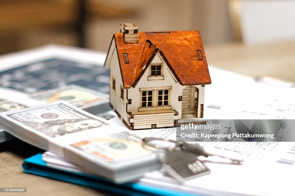 Real estate broker agent house model, money and keys