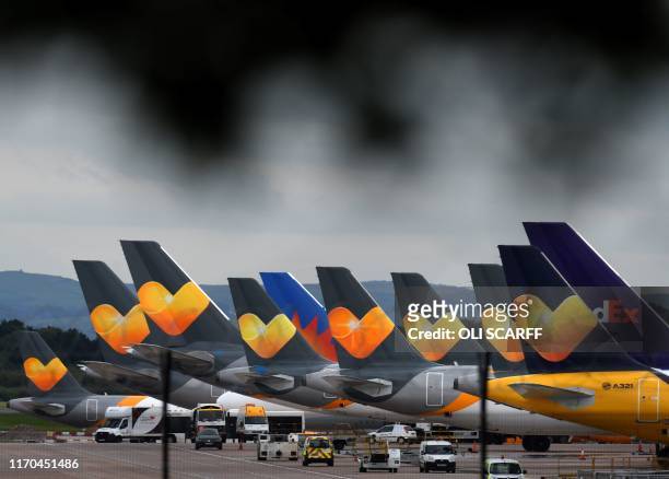Thomas Cook logos are pictured on the tailfins of the company's passenger aircraft parked on tarmac at Manchester Airport in Manchester, northern...