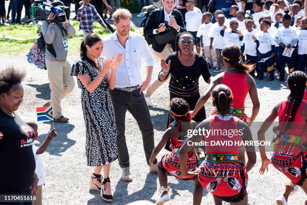 Prince Harry, Duke of Sussex and Meghan, Duchess of Sussex watch dancers performing as they arrive for a visit to the "Justice desk", an NGO in the...