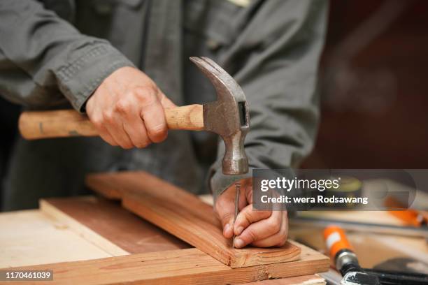 carpenters uses a hammer to driving nail - hammer and nail fotografías e imágenes de stock