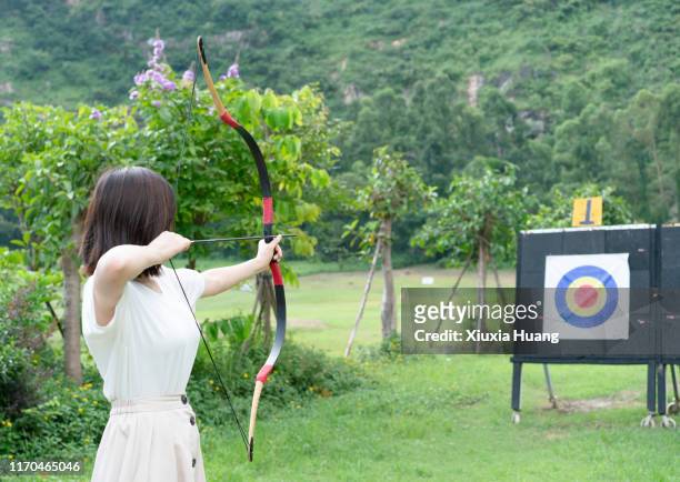 asian woman practicing archery outdoors - arco de arqueiro imagens e fotografias de stock