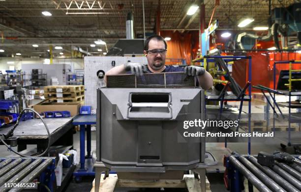 Rodney Harris installs a catalytic converter into a Jøtul wood stove at the company's assembly plant in Gorham. Jøtul has been been a big player in...