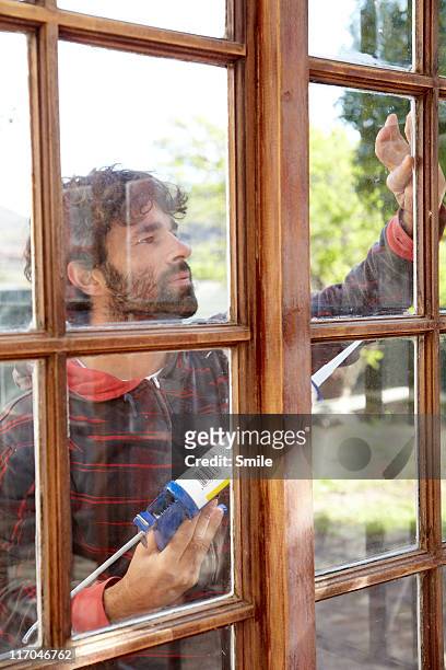 man repairing window frame - caulking stockfoto's en -beelden