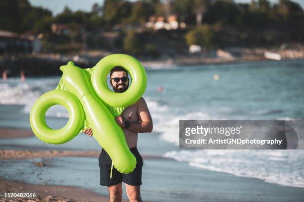 man holding inflatable toy - penis humour stock pictures, royalty-free photos & images