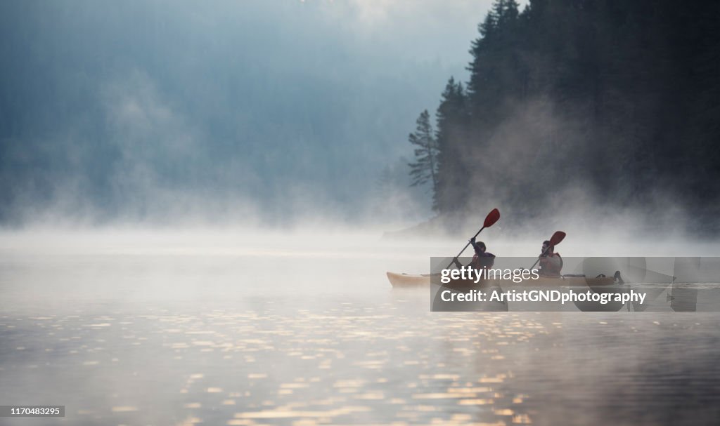 Young couple on kayaking adventure in mountain lake.