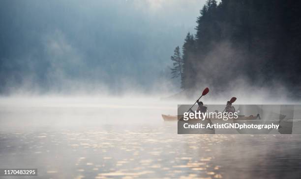 young couple on kayaking adventure in mountain lake. - kayaking stock pictures, royalty-free photos & images