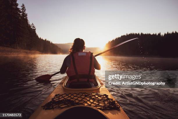 een vrouw met een kajak bij de zonsopgang. - kanoën stockfoto's en -beelden